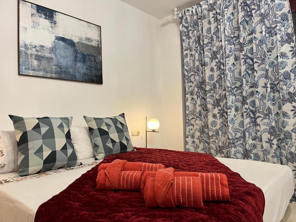 a bedroom with a bed with red sheets and pillows at DREAM BULEVAR in Santa Cruz de Tenerife