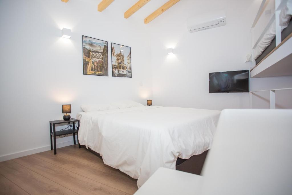a white bedroom with two beds and a tv at Five House 14B in Porto