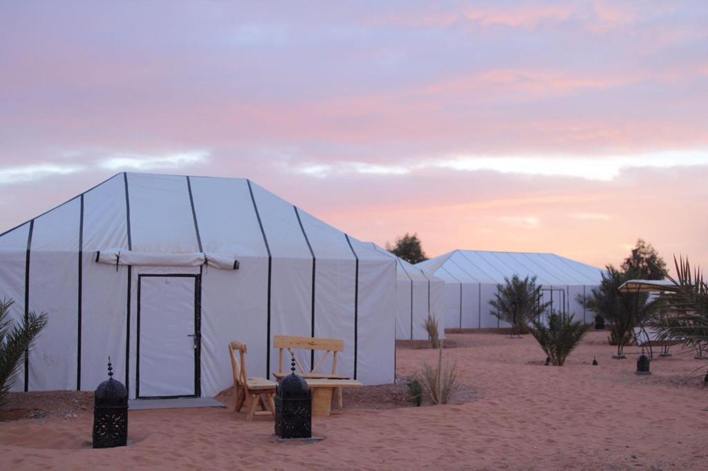 Tienda en el desierto con mesa y sillas en Fantasyland Luxury Camp en Lac Yasmins