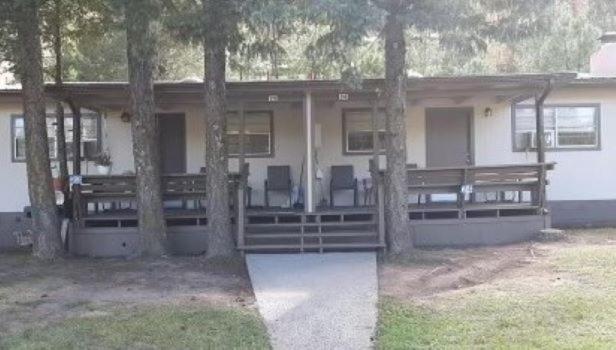 a house with two chairs and trees in front of it at High Country Lodge in Alto