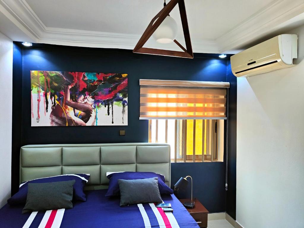 1 dormitorio con 1 cama y una pintura en la pared en Jayé, appart chic à 200m de la plage+ vue sur mer, en Cotonou