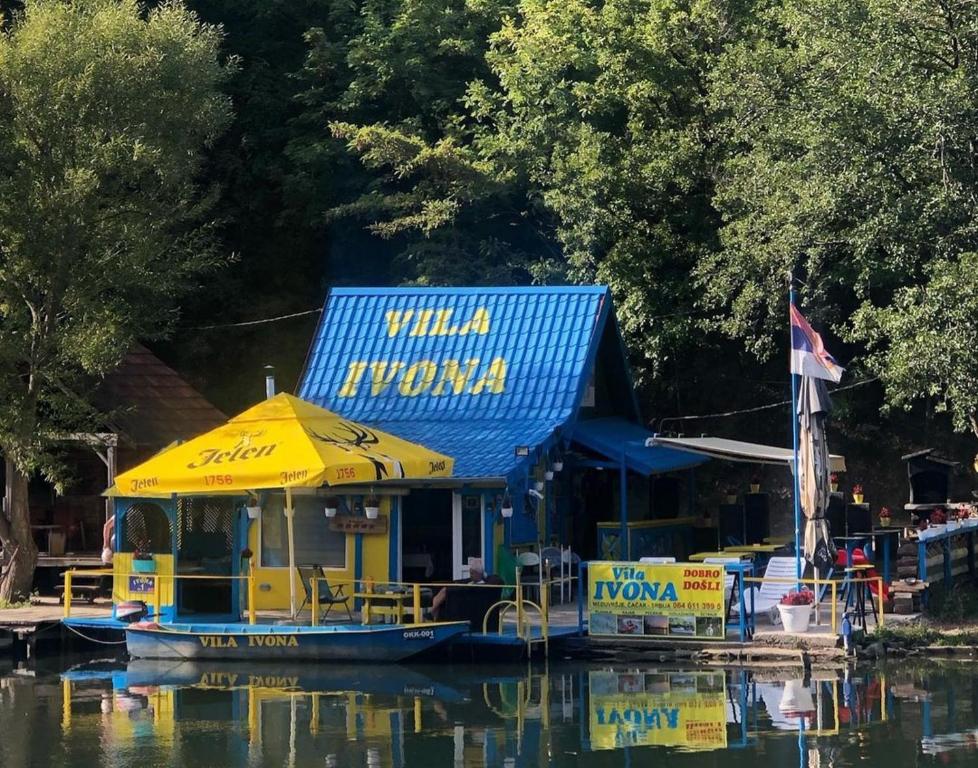 un edificio amarillo y azul en un barco en el agua en Vila Ivona en Čačak
