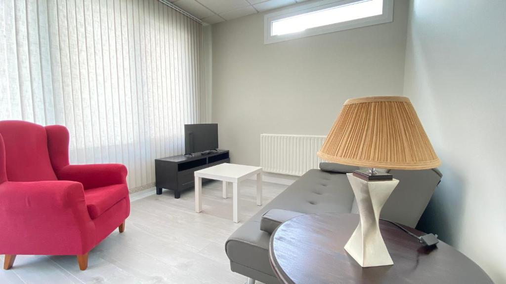 sala de estar con silla roja y mesa con lámpara en Apartamentos Pantón Ribeira Sacra, en Ferreira