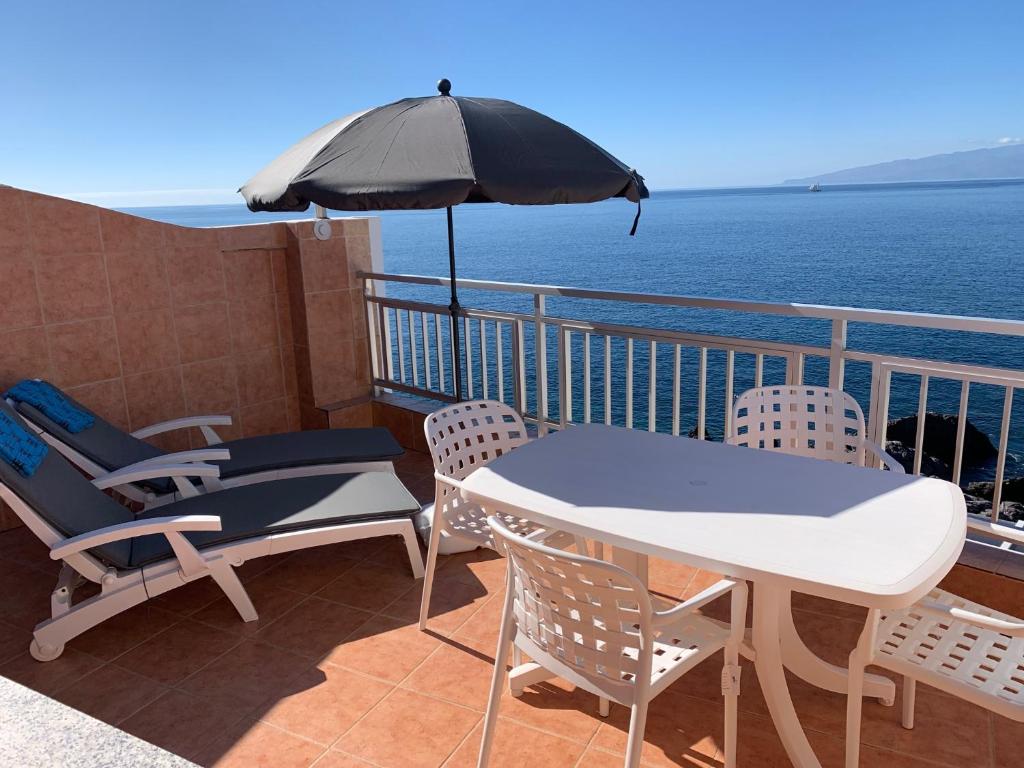 einen Balkon mit einem Tisch, Stühlen und einem Sonnenschirm in der Unterkunft Vivienda Vacacional con Vistas a La Gomera y La Palma in Puerto de Santiago