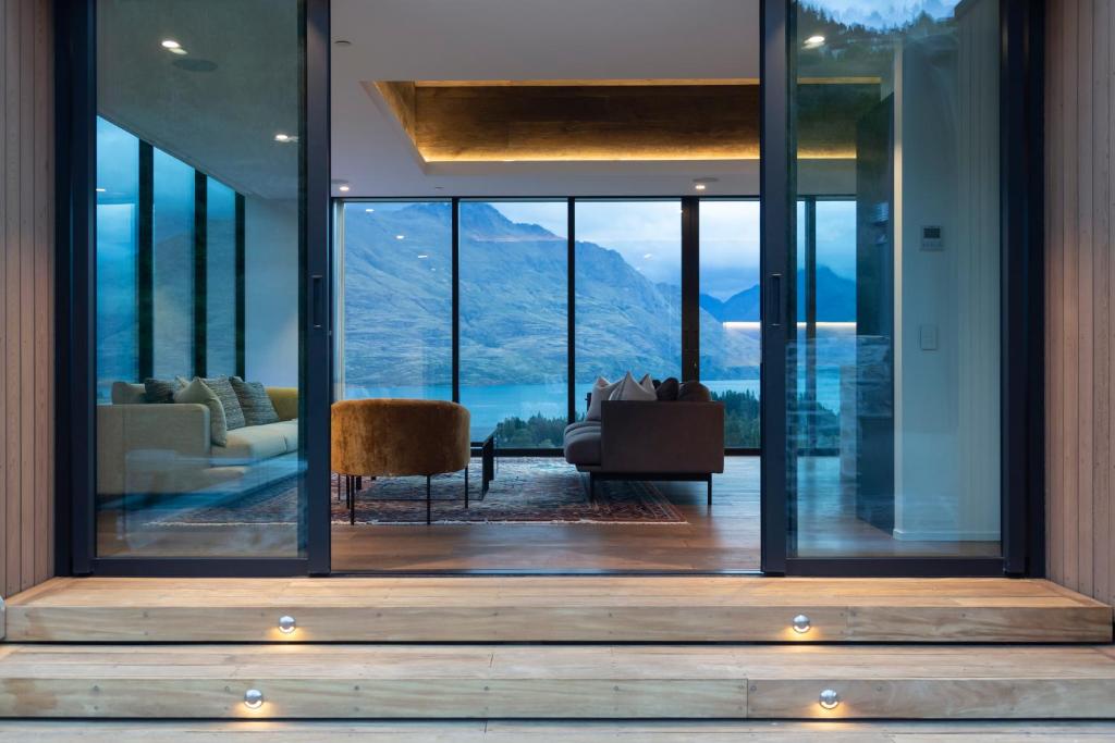 een woonkamer met uitzicht op de bergen door middel van glas bij The Hill Residence in Queenstown