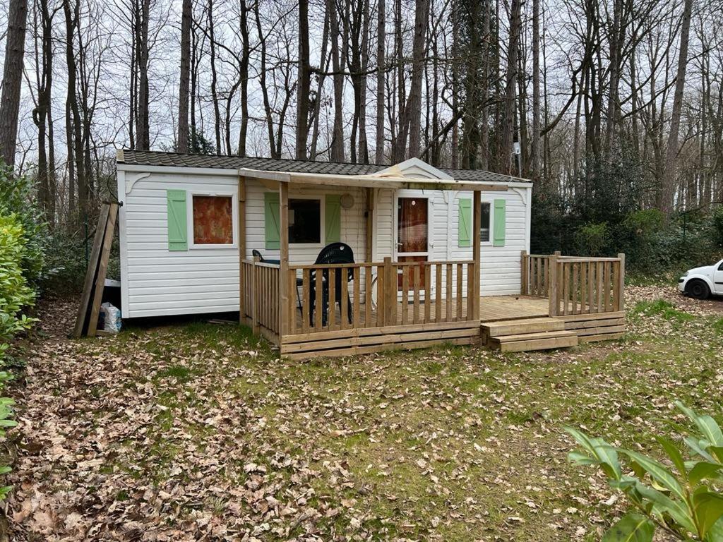 une petite maison avec une terrasse couverte et une terrasse dans l'établissement camping parc des roches, à Souzy-la-Briche