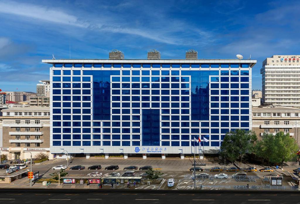 a large blue building with cars in a parking lot at Beijing XinQiao Hotel in Beijing