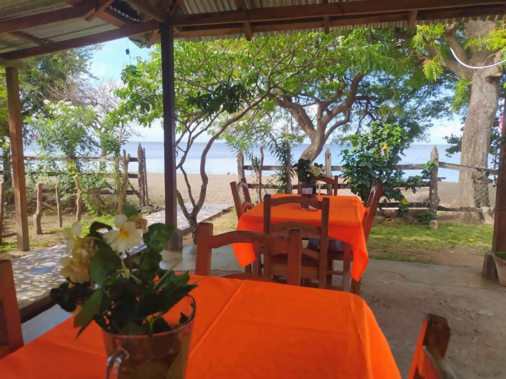 a table with orange tables and chairs with a view of the beach at Hostal La Cascada in Mérida