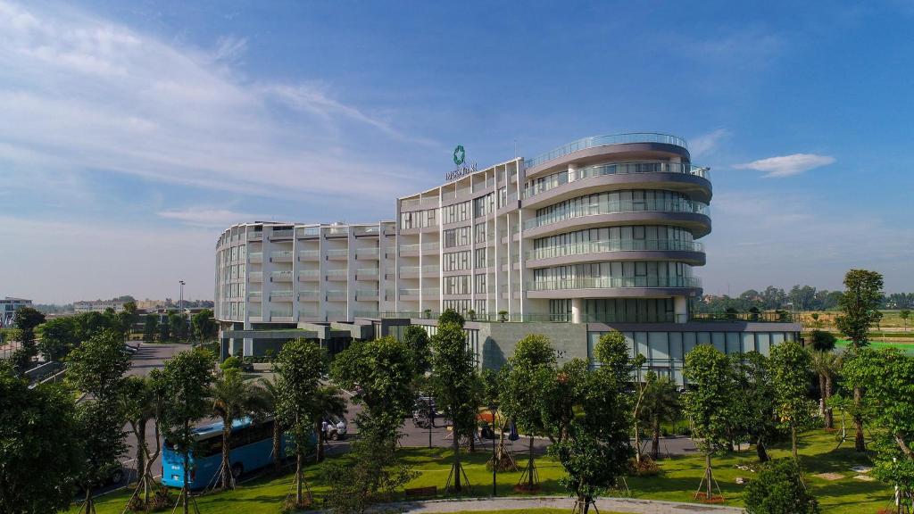 a large building with trees in front of it at DIC Star Hotels & Resorts Vinh Phuc in Yen