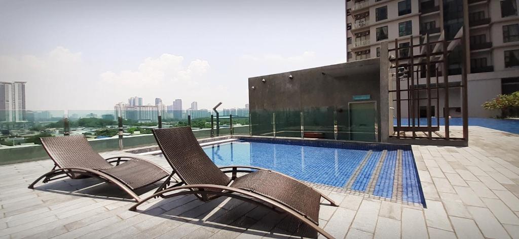 two chairs and a swimming pool on top of a building at Sunway Paradise Home Staycation PH2100 SELF CHECK IN OUT in Subang Jaya