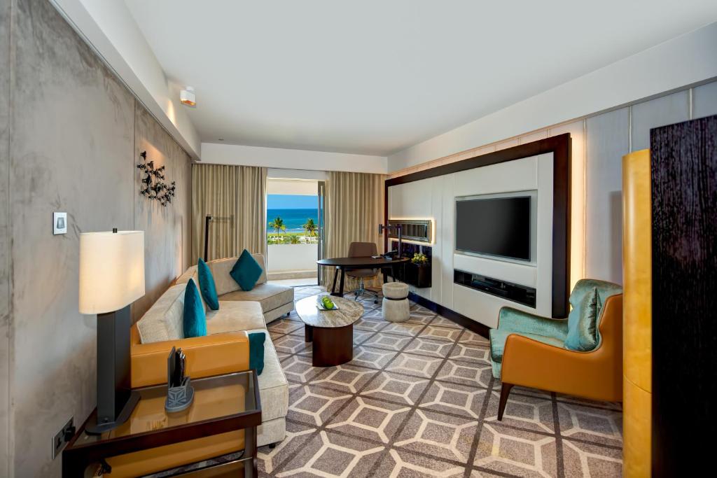 a living room with a couch and a television at InterContinental Muscat by IHG in Muscat