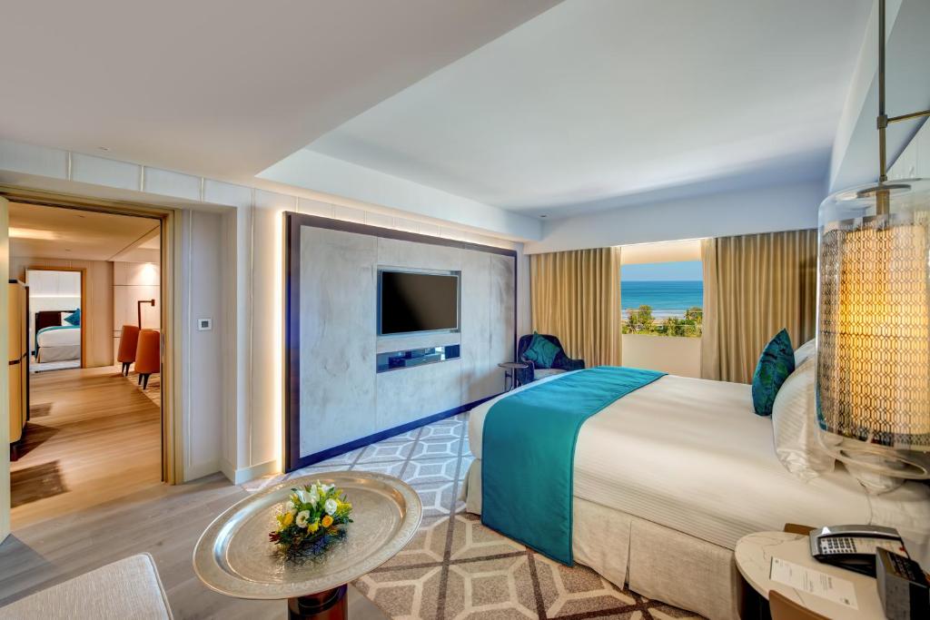a hotel room with a large bed and a living room at InterContinental Muscat by IHG in Muscat