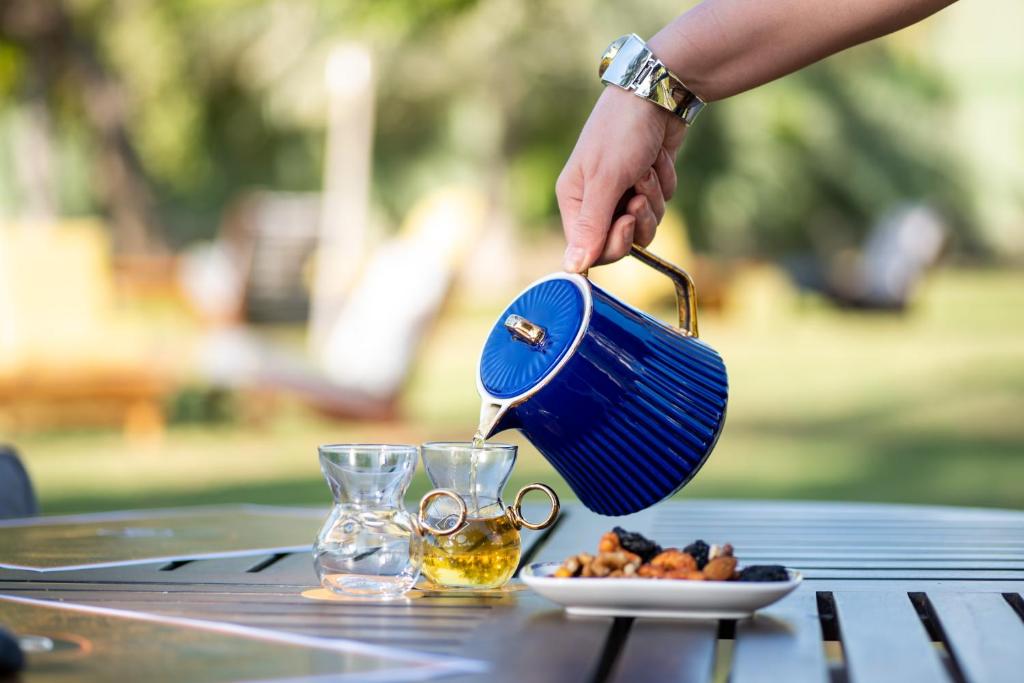 a person pours a drink into a pot on a table at InterContinental Muscat by IHG in Muscat