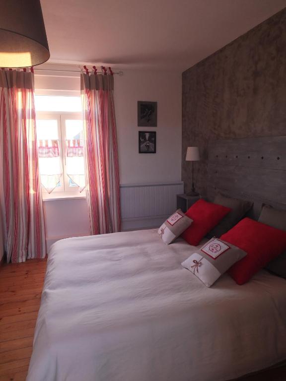 a bedroom with a large white bed with red pillows at La Ceriseraie in La Gorgue