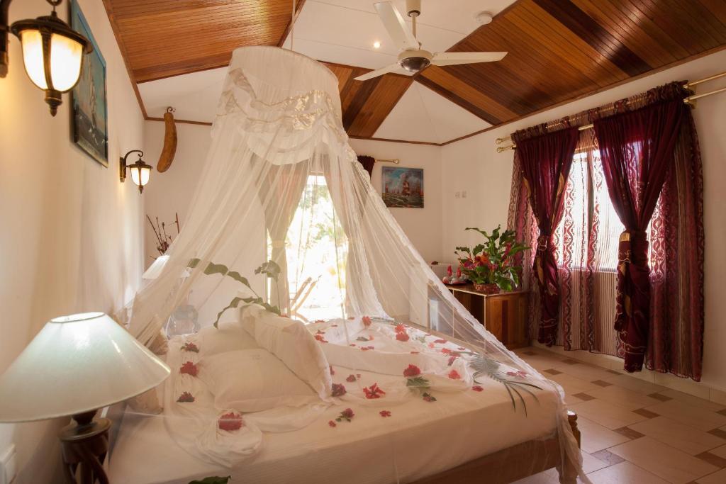 1 dormitorio con 1 cama blanca con dosel en Etoile Labrine Guest House, en La Digue