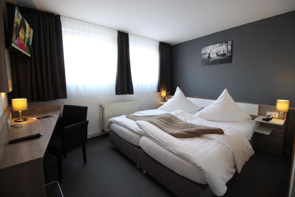 a hotel room with a large bed and a desk at Hotel Restaurant Jägerhof in Braunschweig