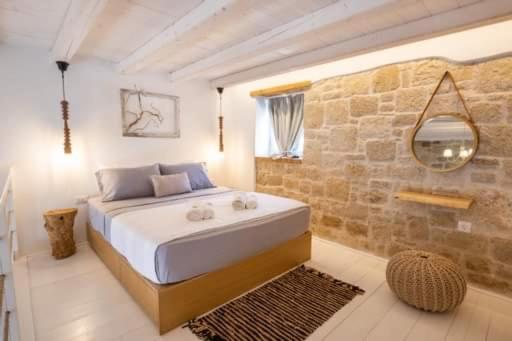 een slaapkamer met een groot bed en een stenen muur bij Grannys Luxury Villas in Karpathos