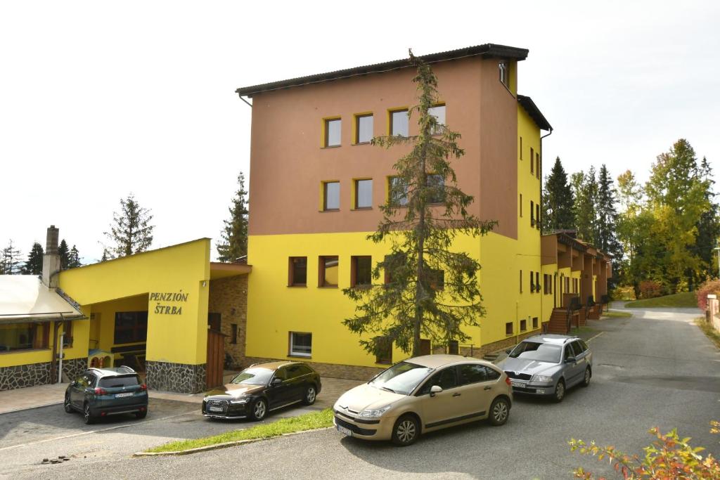 un grupo de coches estacionados frente a un edificio amarillo en Penzión Štrba en Tatranska Strba