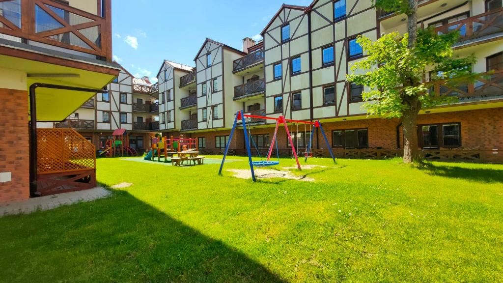 a yard with a playground in front of a building at Apartamenty Przy Brzegu in Rowy