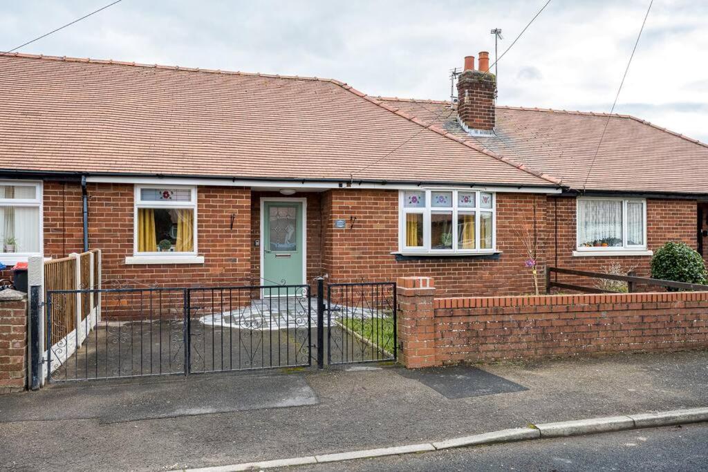 a brick house with a green door and a fence at Cherry Tree Cottage in Thornton