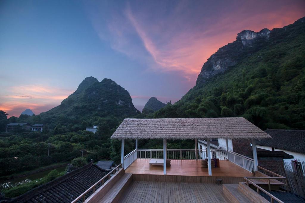 a building with a deck with mountains in the background at Zen Box House in Yangshuo