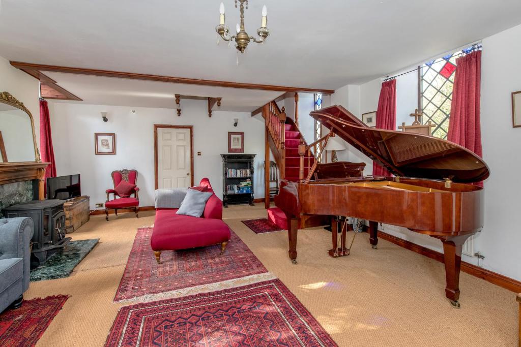 a living room with a piano and red chairs at Stunning baptist chapel with concert piano, pets welcome in Higher Wambrook