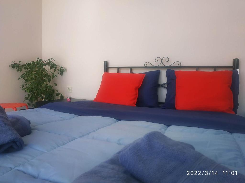 um quarto com uma cama com lençóis azuis e almofadas vermelhas em STUDIOS POSEIDONIA apartments 50 & 70 sqm with sea view em Corinto