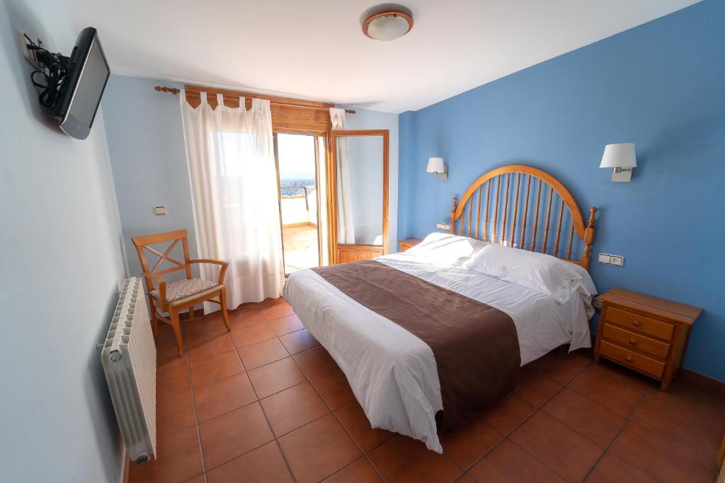 a bedroom with a bed with blue walls and a television at Hostal Gúdar in Gúdar