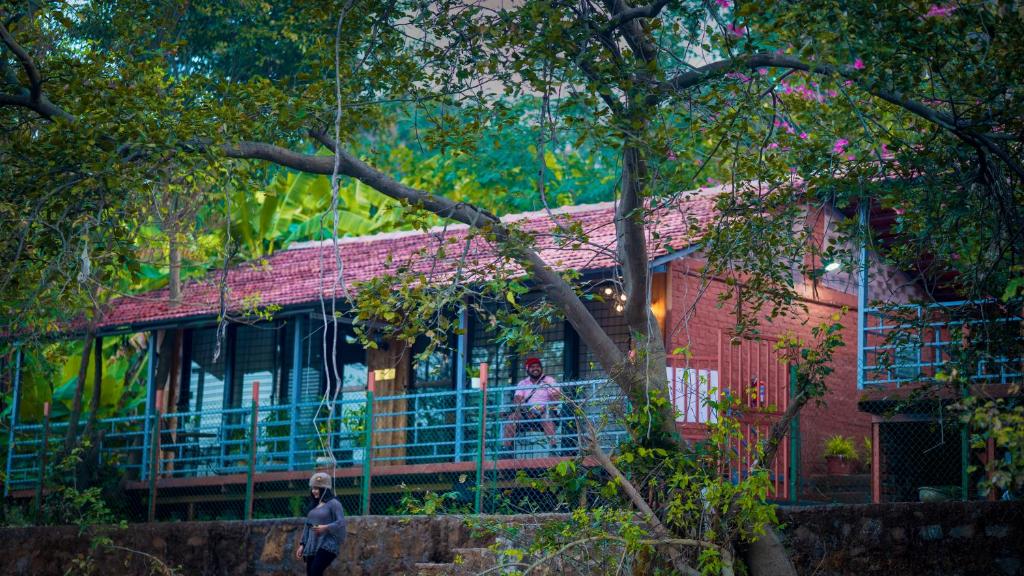 a man standing in front of a red house at Saveda Farm & Cottages in Karjat