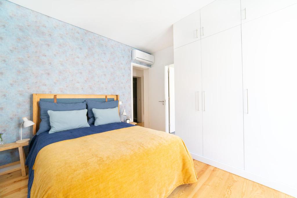 a bedroom with a bed with a yellow blanket at Blue by the River 2 - elegant two-bedroom in Santos in Lisbon
