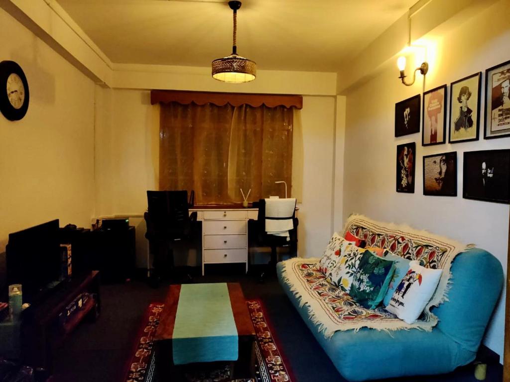 uma sala de estar com um sofá e uma secretária em The Himalayan Workation em Darjeeling
