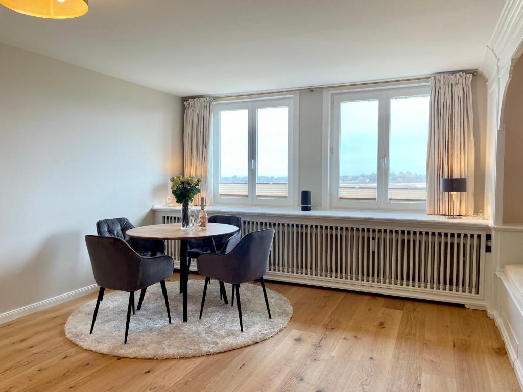 a dining room with a table and chairs and windows at Norderhof Kliffsand 15 in Kampen