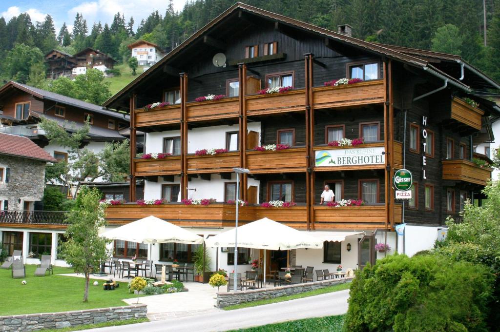un gran edificio con sombrillas blancas delante en Das kleine Berghotel, en Liesing