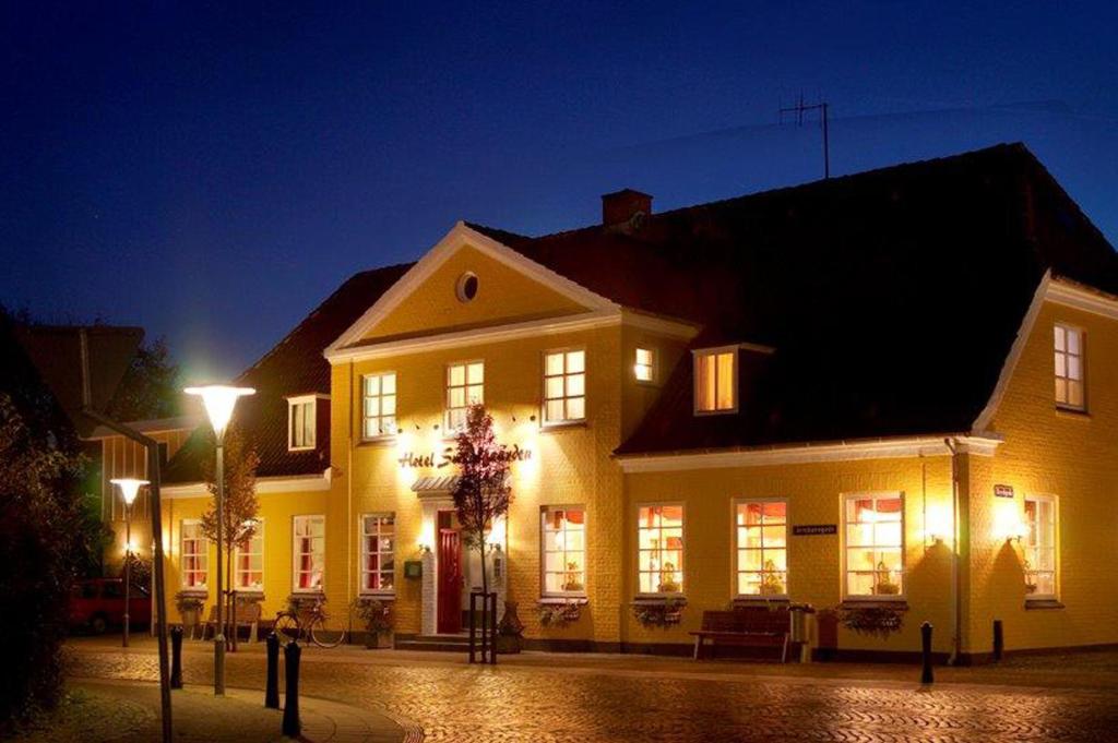 een groot geel huis met lichten op een straat bij Hotel Smedegaarden in Lem