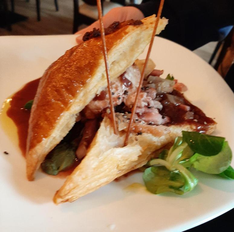 a sandwich on a white plate on a table at Hostellerie de la Poterne in Moncontour