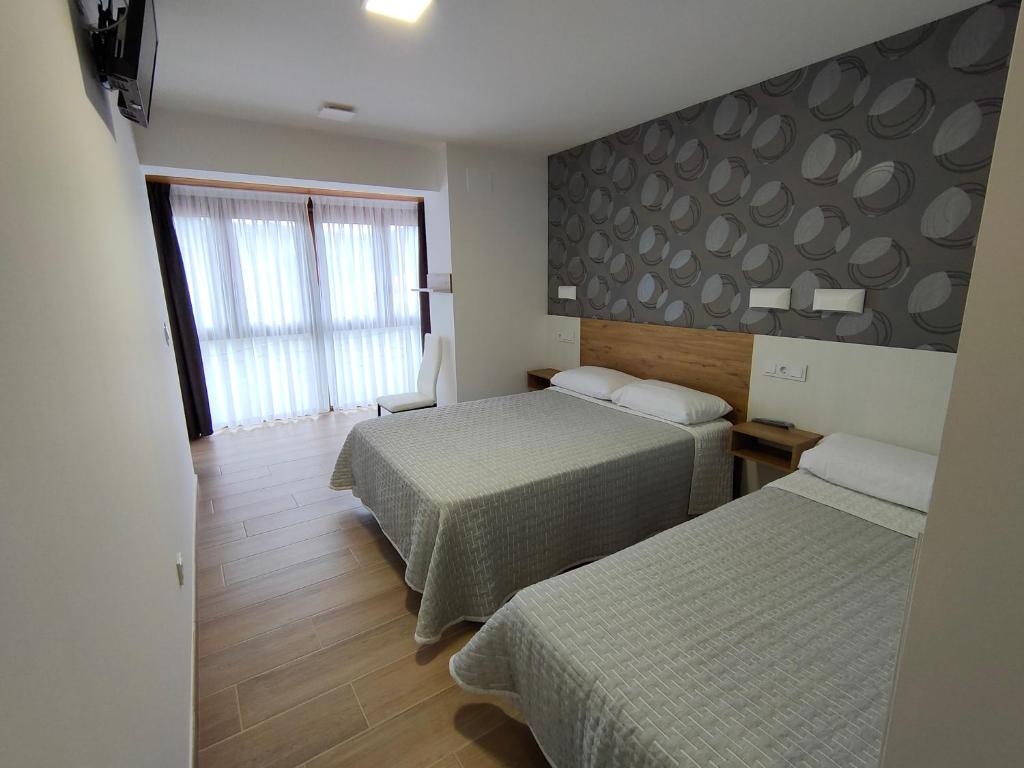 a hotel room with two beds and a window at El Pino in Penagos