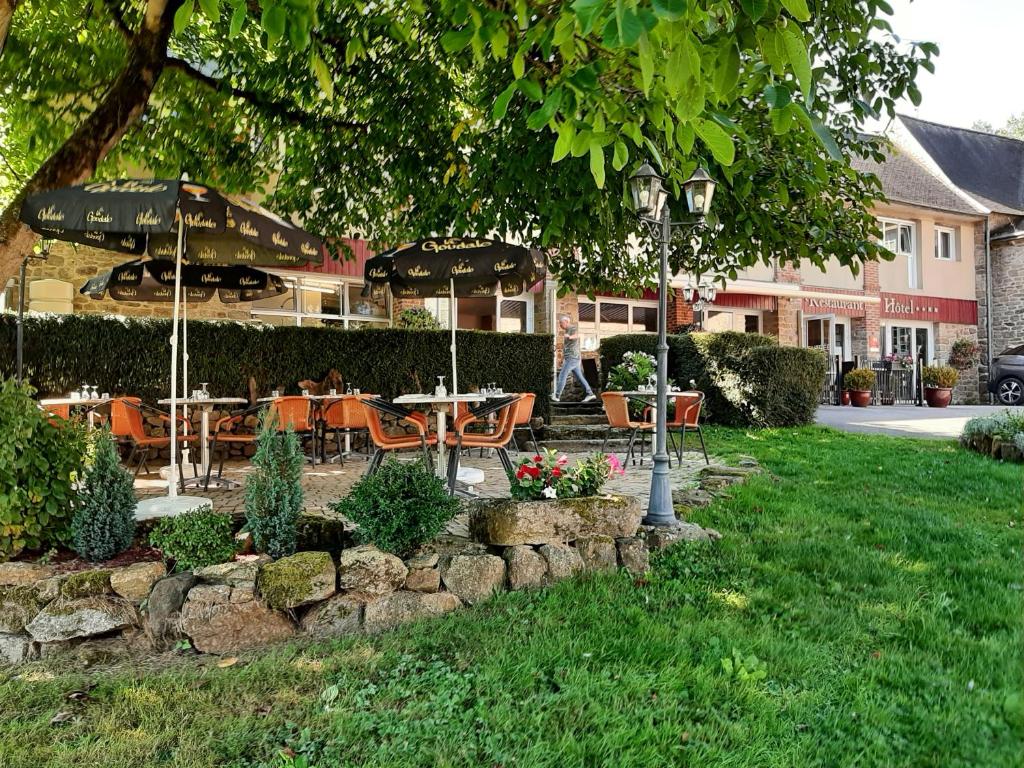 a restaurant with tables and umbrellas in a yard at Hostellerie de la Poterne in Moncontour