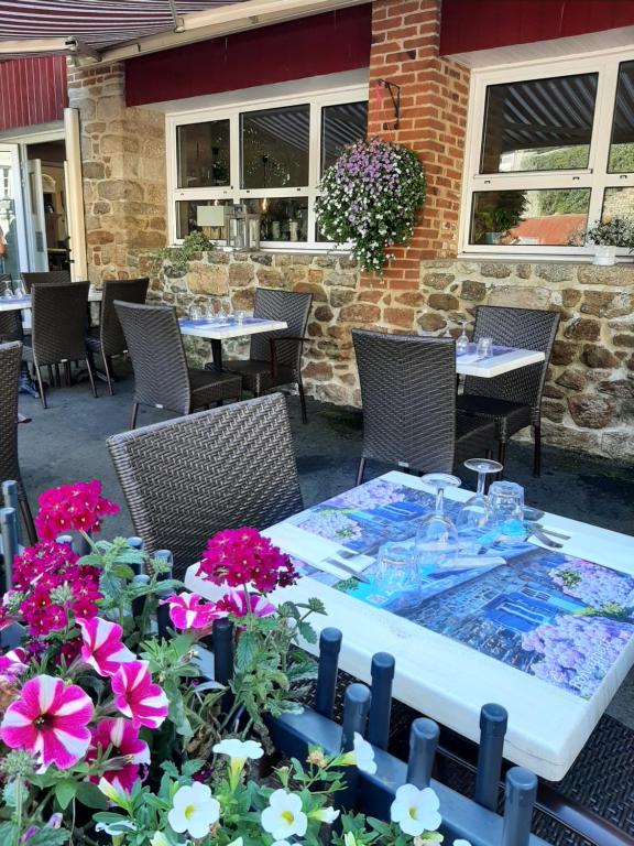 a patio with tables and chairs and flowers at Hostellerie de la Poterne in Moncontour