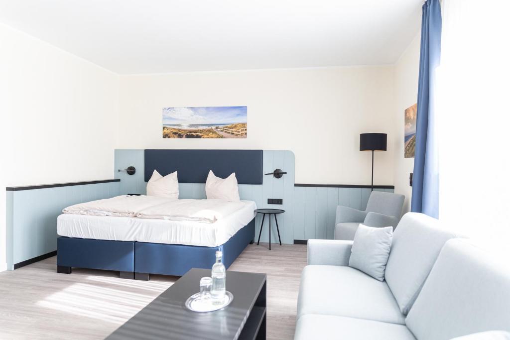 ein Schlafzimmer mit einem Bett und ein Wohnzimmer mit einem Sofa in der Unterkunft TIDE Hotel in Wilhelmshaven