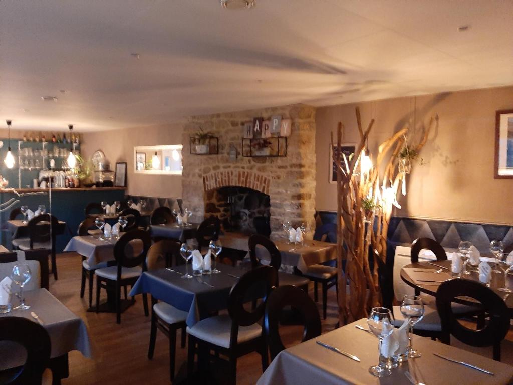 a restaurant with tables and chairs and a fireplace at Hostellerie de la Poterne in Moncontour