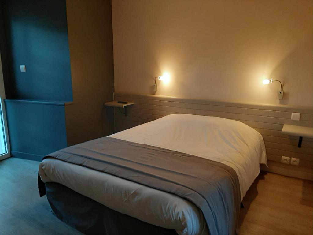 a bed in a room with two lights on the wall at Hostellerie de la Poterne in Moncontour
