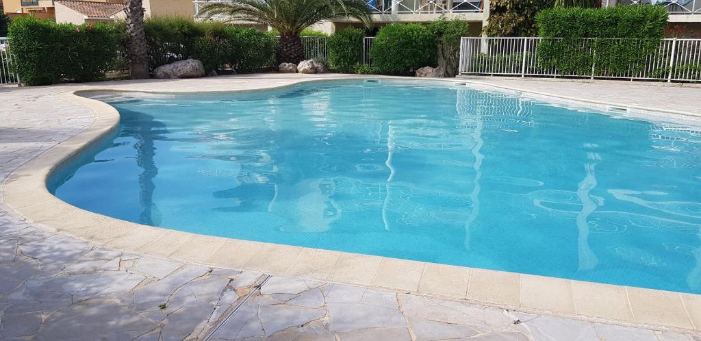 een groot zwembad met blauw water bij Les 5 palmiers in Valras-Plage