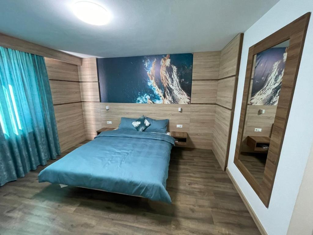 a bedroom with a blue bed and a painting on the wall at Motel "KULA" in Cazin