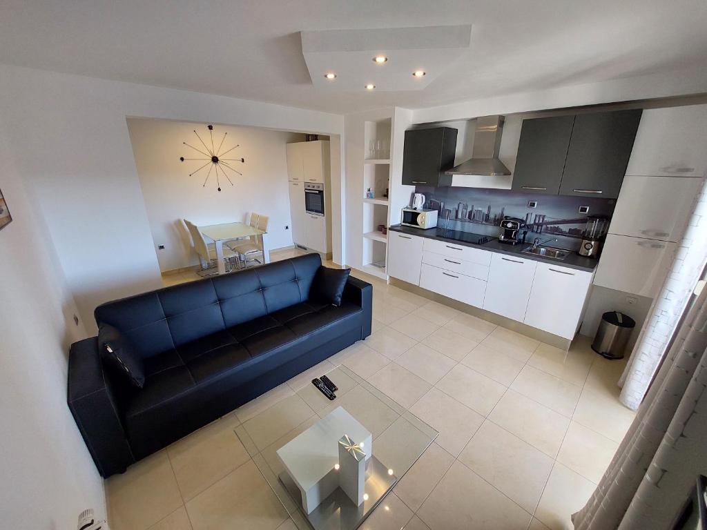 a living room with a black couch and a kitchen at Apartments Daniel in Vodice