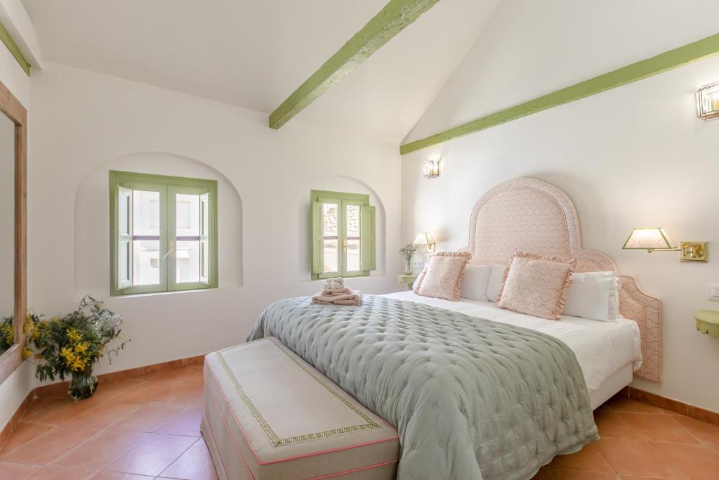 um quarto com uma cama grande e 2 janelas em La Abadia de Giralda em Sevilha