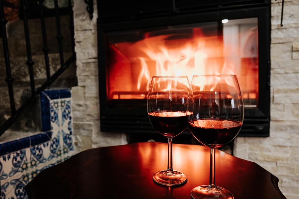 two glasses of wine sitting on a table in front of a fireplace at Casa Rural El Puente Grande in Navahermosa