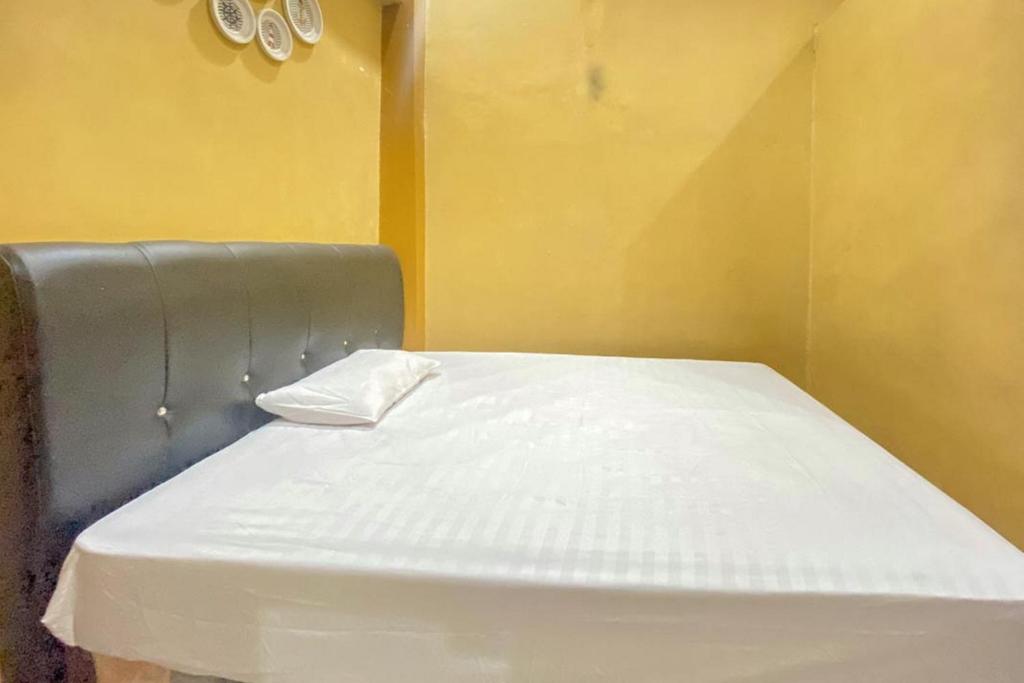 ein leeres Bett in einem Zimmer mit gelber Wand in der Unterkunft Home Stay Mulyawan Syariah Sengkang Mitra RedDoorz in Singkang