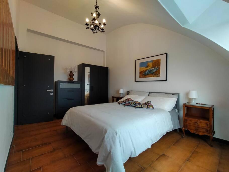 Un dormitorio con una gran cama blanca y una lámpara de araña. en Il Trifoglio: sobrio ed accogliente trilocale, en Rozzano
