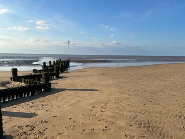 - une plage avec une rangée de postes en bois sur la plage dans l'établissement Gone To The Beach Flat 1, à Hunstanton