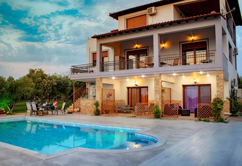 a villa with a swimming pool in front of a house at Villa Scorpion Nea Moudania Halkidiki in Nea Moudania